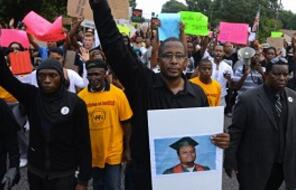 National President of Black Lawyers for Justice, carries a picture of Michael Brown as he leads demonstrators on a march.