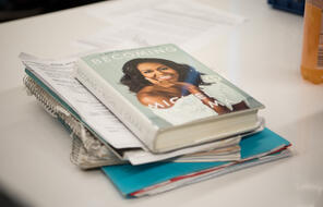 A stack of papers with Michelle Obama's "Becoming" on top.