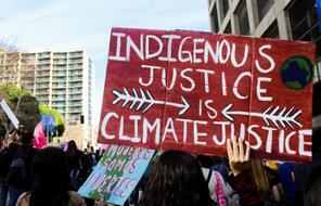 Indigenous Justice is Climate Justice sign in crowd protesting for environmental justice. 