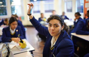 Uniformed student raises her hand. 