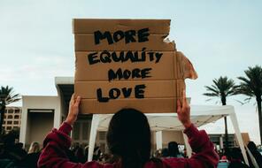 Person Holding Sign above their head that says More Equality More Love