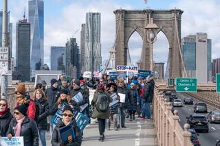 Photo antisemitism protesters marching over bridge.