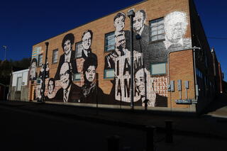 A view of the Memphis Upstanders Mural, a painting on a brick building featuring many prominent historical figures in black and white.
