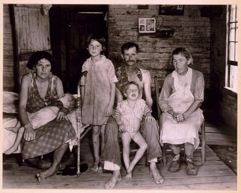 Three adults and three children pose for the photo in a small room, circa mid-1930s.