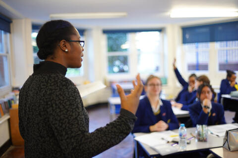 An educator speaks at the front of a classroom