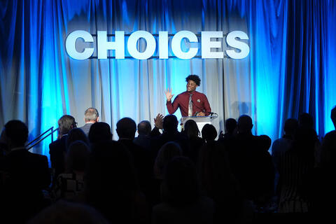 Man on stage at FHAO event with the word CHOICES highlighted in the background