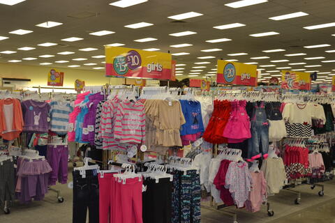Interior of a department store featuring the girls' clothing section.
