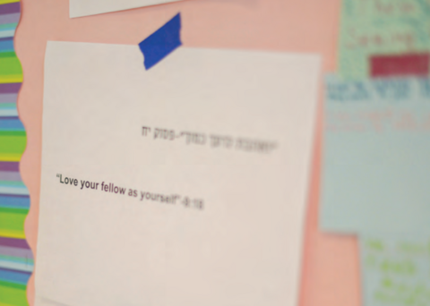 A piece of paper reading "Love Your Fellow as Yourself" in English and Hebrew.