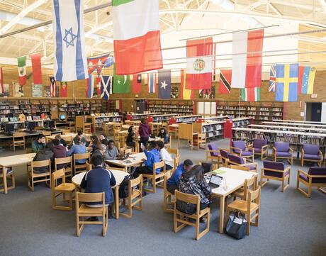 A school library with flags of many nations hanging from the ceiling.