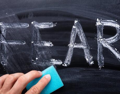 The word "FEAR" is being erased from a blackboard.